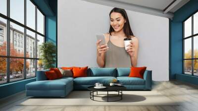 Portrait of a smiling asian woman holding takeaway coffee Wall mural