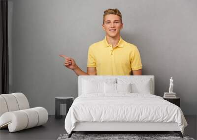 Portrait of a smiling casual teenage boy pointing Wall mural