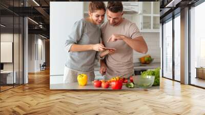 Portrait of a smiling loving couple cooking salad together Wall mural