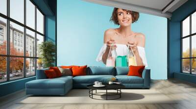 Portrait of a smiling pensive woman holding shopping bags Wall mural