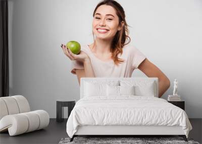 Portrait of a smiling pretty girl holding an apple Wall mural