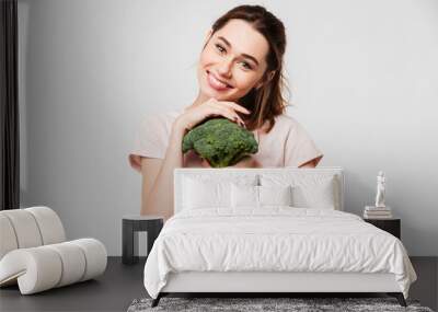 Portrait of a smiling pretty girl holding broccoli Wall mural