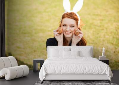 Portrait of a smiling red head woman wearing bunny ears Wall mural