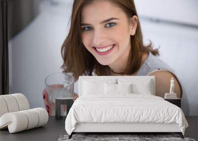 Portrait of a smiling woman holding glass of water Wall mural