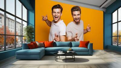 Portrait of a two happy young men best friends pointing fingers Wall mural