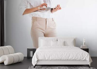 Portrait of adorable smiling woman with long brown hair holding and looking at silver laptop, isolated over white background in studio Wall mural