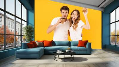 Portrait of attractive couple man and woman smiling at camera while standing together and drinking coffee from takeaway cup Wall mural