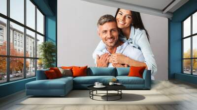 Portrait of beautiful couple man and woman in basic clothing smiling and hugging together, isolated over gray background Wall mural