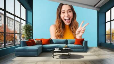 Portrait of beautiful joyous woman smiling and gesturing peace sign Wall mural