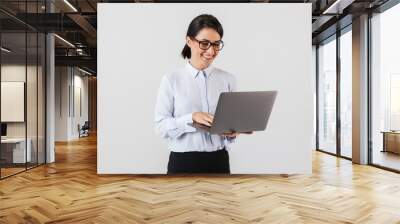 Portrait of businesslike woman wearing eyeglasses holding silver laptop in the office, isolated over white background Wall mural