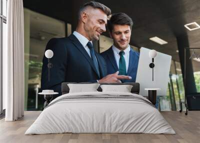 Portrait of caucasian businessmen partners standing outside office center and using laptop together during working meeting Wall mural