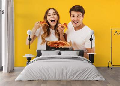 Portrait of caucasian couple man and woman in basic t-shirts smiling while eating pizza from box Wall mural