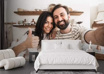 Portrait of caucasian couple taking selfie photo while cooking in kitchen at home Wall mural