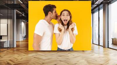 Portrait of caucasian man whispering secret or interesting gossip to excited woman in her ear Wall mural