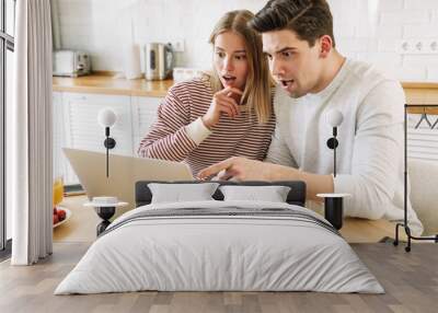 Portrait of couple pointing finger at laptop while having breakfast Wall mural