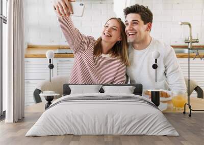 Portrait of couple taking selfie on smartphone while having breakfast Wall mural