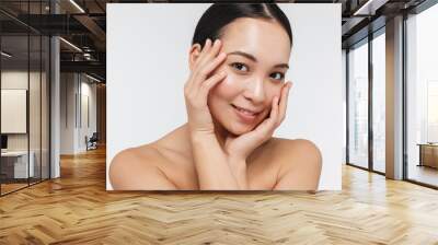 Portrait of cute half naked asian woman touching her clear skin and looking at camera Wall mural