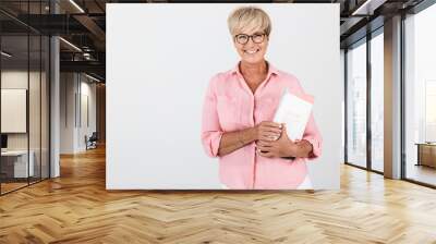 Portrait of happy adult woman wearing eyeglasses holding studying book Wall mural