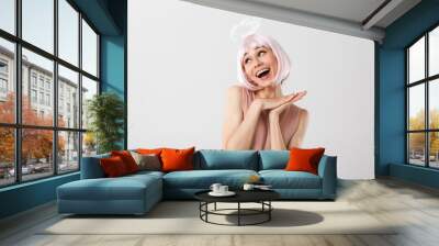 Portrait of happy lovely woman wearing pink wig and toy halo looking aside at copyspace while smiling Wall mural