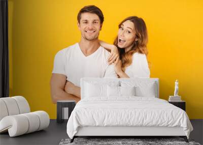 Portrait of joyous couple man and woman in basic t-shirts smiling and hugging together Wall mural