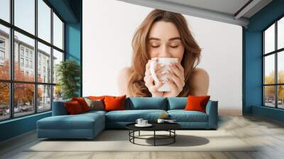 Portrait of lovely woman with beautiful brown hair drinking morning coffee or tea, while resting in bed Wall mural