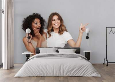 Portrait of two cheerful young women standing together Wall mural