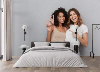 Portrait of two cheerful young women standing together Wall mural