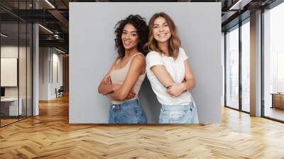 Portrait of two cheerful young women standing together Wall mural