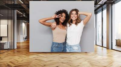 Portrait of two happy young women standing together Wall mural