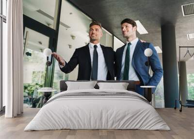 Portrait of two pleased businessmen partners talking together while walking outside job center during working meeting Wall mural