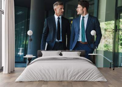 Portrait of two serious businessmen partners having conversation outside job center during working meeting Wall mural