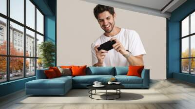 Portrait of unshaven excited man playing online game on mobile phone Wall mural