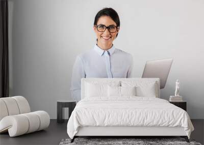 Portrait of young businesswoman wearing eyeglasses holding silver laptop in the office, isolated over white background Wall mural