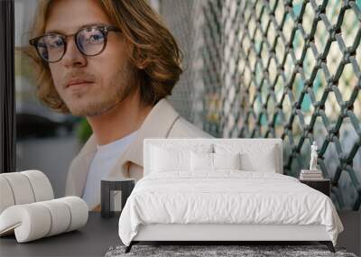 Portrait of young handsome long-haired smiling man in glasses Wall mural