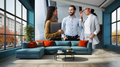 Portrait of young successful multinational colleagues working in office Wall mural