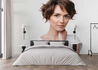 Portrait of young woman with short brown hair in basic t-shirt looking at camera Wall mural