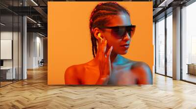 Pretty beautiful young african naked woman posing isolated over yellow neon lights wall background listening music with headphones wearing sunglasses. Wall mural