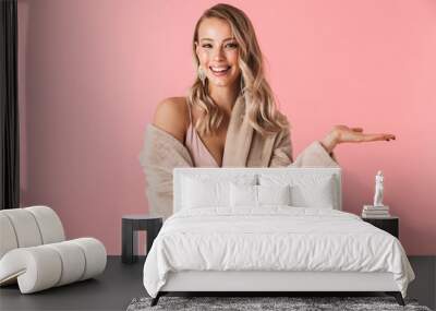 pretty woman posing isolated over pink wall background dressed in fashion coat. Wall mural