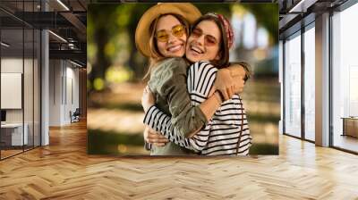 Pretty young happy women friends walking outdoors Wall mural