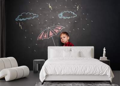 Sad kid holding umbrella on the chalkboard with drawings Wall mural