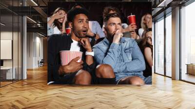 Scared young friends sitting in cinema watch film Wall mural