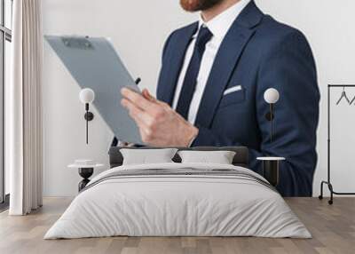 Serious businessman posing isolated over white wall background holding clipboard. Wall mural