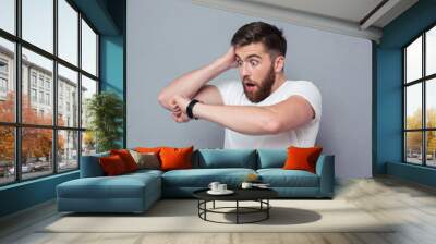 Shocked man looking on wrist watch Wall mural