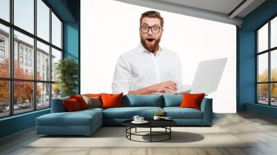 Shocked young bearded man using laptop. Wall mural