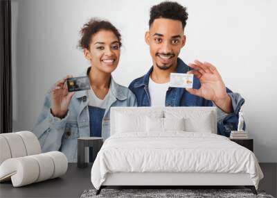 Smiling african couple in denim shirts holding credit cards Wall mural