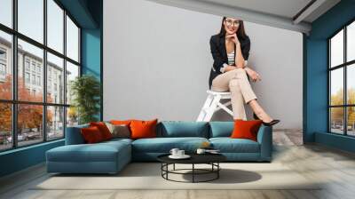 Smiling asian business woman in eyeglasses sitting on chair Wall mural