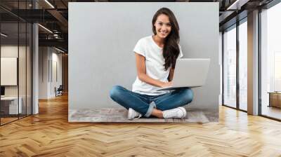 Smiling asian woman working on laptop computer Wall mural