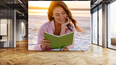 Smiling beautiful young woman reading a book Wall mural