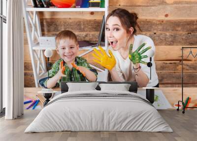 Smiling boy and mother showing hands painted in colorful paints Wall mural