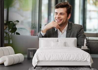 Smiling business man sitting by the table in cafe Wall mural